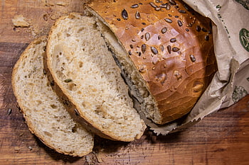 slice of bread, brown seeded bread, rustic wooden cutting board, paper bag, close-up bread, sliced bread, bread loaf, bread texture, bread crust, bread interior, bread seeds
