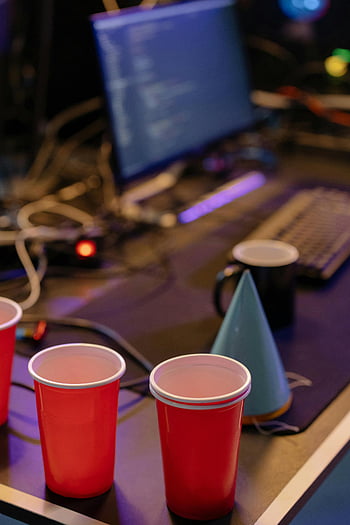 red disposal cups, party hat, computer desk, festive office, red cups, office setup, computer monitor, keyboard, office party, desk setup, party decoration