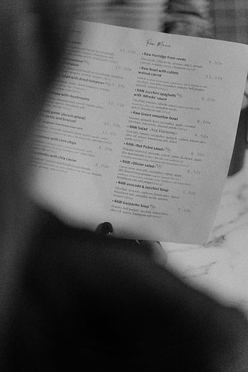 grayscale photo, person holding menu, restaurant menu, close-up menu, black and white, menu in use, food menu, dining menu, menu details, menu text, menu items