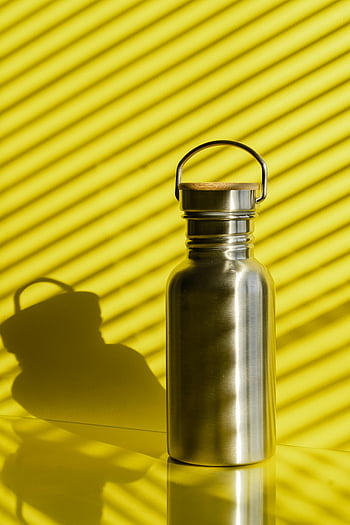 metallic flask, stainless steel flask, vibrant yellow background, striped shadows, stylish flask, yellow background, flask shadow, modern flask, reflective surface, water bottle, eco-friendly flask