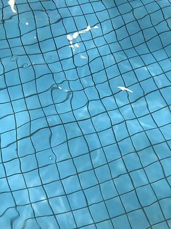 swimming pool, blue bottom, serene water, light reflections, sunny day, ripples, close-up view, pool tiles, clear water, outdoor pool, tranquil scene