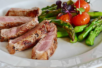 grilled meat dish, white plate, grilled steak slices, asparagus, cherry tomatoes, healthy meal, close-up, grilled steak, asparagus spears, white plate presentation