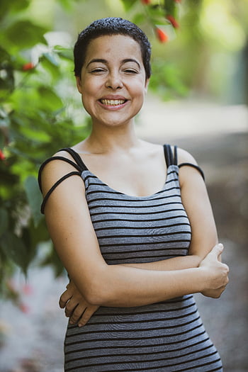 woman, gray and black striped, spaghetti strap dress, standing, laughing, joyful, short hair, smiling, greenery, outdoor, casual fashion