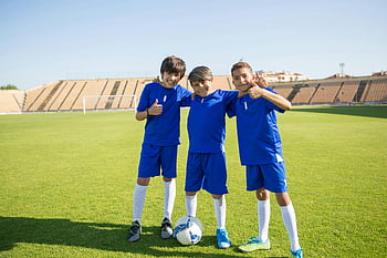 chlapci v uniformě, fotbalové hřiště, Modré uniformy, mladí kluci, fotbalový míč, slunečný den, představují, tři chlapci, sportovní, venkovní, stadión