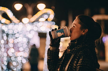 woman, coffee, outdoors, night, twinkling Christmas lights, festive atmosphere, winter, city, illuminated Christmas tree, enjoying, warm coffee