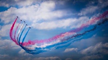 airplanes performing aerobatics, colorful smoke trails, clear blue sky, stunning aerobatic display, airshow, aerial performance, sky show, aviation, jet planes, air tricks, smoke effects