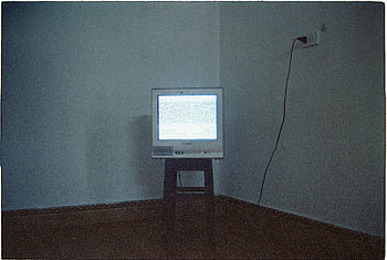 vintage CRT television, static noise, minimalist room, TV on chair, corner setting, retro TV, minimalist decor, static display, vintage electronics, minimalist interior, corner placement