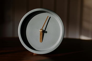 graue runde Uhr, Holzoberfläche, minimalistischer Wecker, sanfte Beleuchtung, warmes Licht, Entwurfsthemen, Zeit Themen, elegante Uhr, Schatten werfen, Analoge Uhr, minimalistisches Design