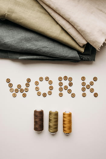 brown buttons, sewing threads, artistic arrangement, work spelled, sewing materials, fabric rolls, thread spools, creative display, textile art, craft supplies, flat lay photography
