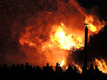 Person Near Fire, large fire, night scene, people watching, surrounded by smoke, sparks, night fire, fire illumination, crowd watching fire, fire event, night fire scene