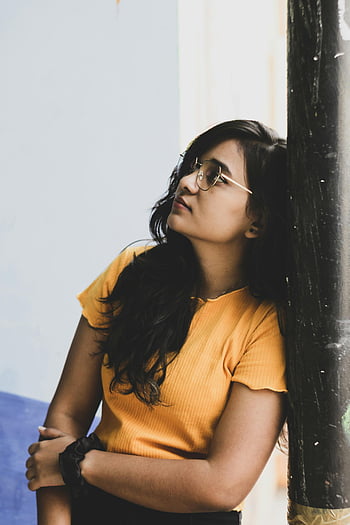 Dívka ve žluté košili, opřený o černou tyč, Portrét mladé ženy, Patna Indie, Promyšlený pohled, vzhůru pohled, příležitostná pozice, městském prostředí, pouliční fotografie, přirozené světlo, upřímný okamžik