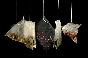 tea bags, herbal blends, clear plastic packs, hanging tea bags, black backdrop, assorted tea, tea packaging, herbal tea, tea varieties, tea sachets, tea collection