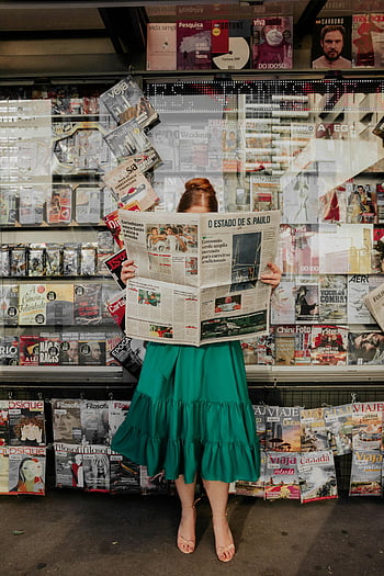 woman in dress, reading newspaper, street magazine stand, green dress, outdoor scene, newsstand, urban setting, daily life, public space, female reader, newspapers