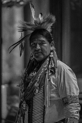 traditional Indigenous clothing, North American Indigenous, black and white portrait, cultural heritage, traditional attire, Indigenous man, feather headdress, cultural representation, Indigenous culture, traditional Indigenous, black and white photography