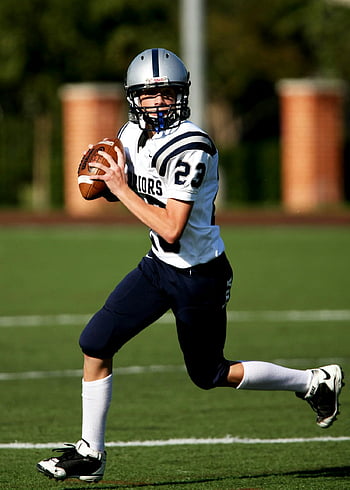 American football, quarterback, running, sunny day, game, field, young player, sports, action, helmet, uniform