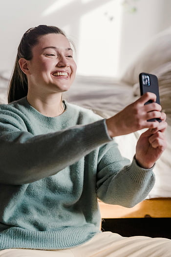 usmívající se žena, s selfie, chytrý telefon, útulný domov, moderní životní styl, Selfie okamžik, Domácí prostředí, žena s úsměvem, chytrý telefon selfie, Útulná atmosféra, životní styl fotografie