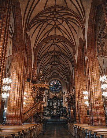 cihlový kostel, Interiér gotické církve, symetrický pohled, lustry, růžice, složité oblouky, náboženské prvky, klidná atmosféra, vitráž, katedrální architektura, Vzhled interiéru