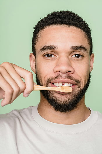 man in white crew neck shirt, bamboo toothbrush, brushing teeth, sustainability, close-up portrait, eco-friendly, dental hygiene, man brushing teeth, sustainable living, green background, beard