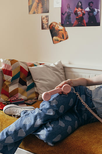 90s style bedroom, denim jeans, cassette tapes, vintage telephone, telephone handset, nostalgic room, heart pattern jeans, colorful pillows, wall posters, casual sneakers, cozy couch