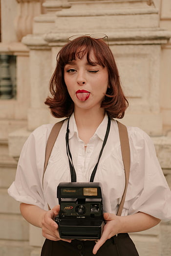 nainen kameralla, vintage-kamera, seepiasävyjä, leikkisä pose, polaroidikamera, vanha kamera, nainen valokuvaaja, retro-tyyli, ulkona oleva muotokuva, klassinen kamera, naaras kameralla