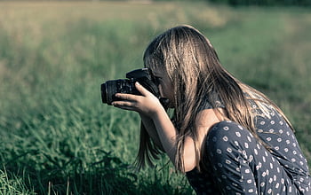 Dívka drží DSLR kameru, zelené louky, Mladá dívka fotografie, fotografování přírody, venkovní fotografie, travnaté fotky v terénu, Dívka fotografuje, Použití DSLR fotoaparátu, Outdoor DSLR Photography, Dívka fotografka, Fotografie přírody
