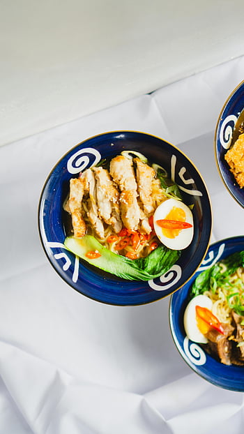ramen dish, chicken ramen, vibrant vegetables, white table, top view, savory chicken, ramen bowl, blue bowl, egg, noodles, bok choy
