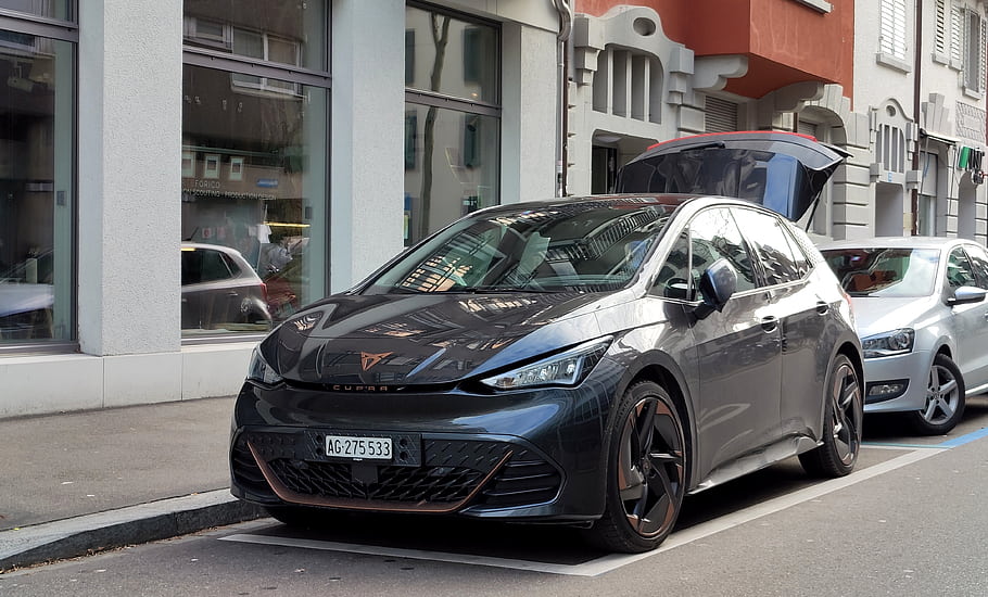 cupra, narozený, elektrické auto, hatchback, městské ulice, moderní design, černé auto, otevřený kufr, panoráma města, zaparkované auto, poznávací značka