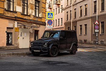 Black Mercedes AMG G63, urban city street, historic buildings, daylight setting, black SUV, parked car, cityscape, street scene, Mercedes-Benz, luxury vehicle, urban environment