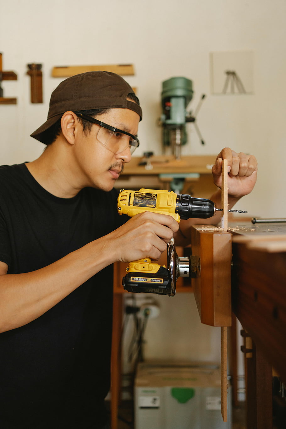 man, safety glasses, drilling, wooden plank, concentrated carpenter, workshop setting, drill, young carpenter, safety equipment, woodworking, carpentry tools