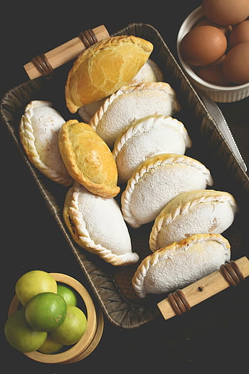 Peruvian empanadas, rustic basket, fresh eggs, limes, delicious empanadas, baked empanadas, food photography, traditional cuisine, appetizing empanadas, Peruvian food, basket presentation