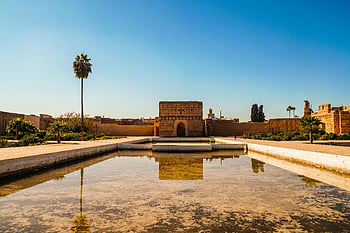 El Badi Palace, Marrakech, reflecting pool, clear blue sky, historic architecture, Morocco, palm trees, desert landscape, travel destination, cultural heritage, Marrakesh