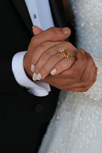 bride and groom, holding hands, close-up, engagement ring, wedding attire, wedding dress, tuxedo, wedding couple, romantic moment, wedding photography, hand in hand