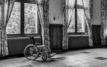 grayscale photo, wheelchair, empty room, large windows, black and white, wheelchair by windows, empty wheelchair, indoor wheelchair, wheelchair in room, wheelchair photography, wheelchair in black and white
