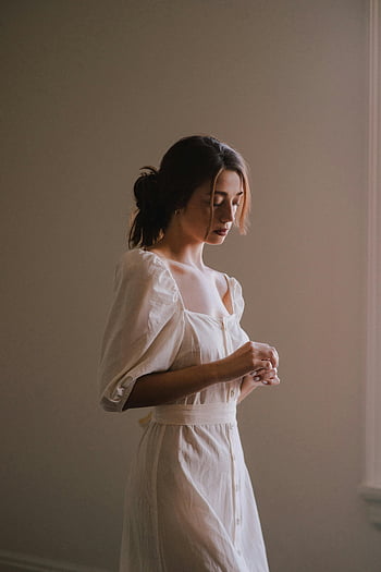 dreamy young woman, white dress, light room, serene, soft indoor lighting, graceful, indoor portrait, natural light, elegant, minimalist, calm atmosphere