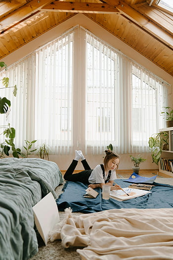 attic room, young girl painting, bright room, natural light, plants, white shirt, floor painting, cozy space, artistic activity, indoor plants, wooden ceiling