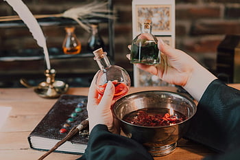 wizarding world, colorful potions, spellbook, wand, close-up shot, hands mixing, themed setup, glass bottles, magical elements, fantasy scene, potion making