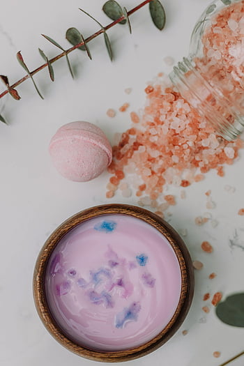 spa setup, pink bath salts, bowl of lotion, eucalyptus leaves, relaxing atmosphere, pink and white round ornament, bath bomb, spa treatment, self-care, wellness, aromatherapy