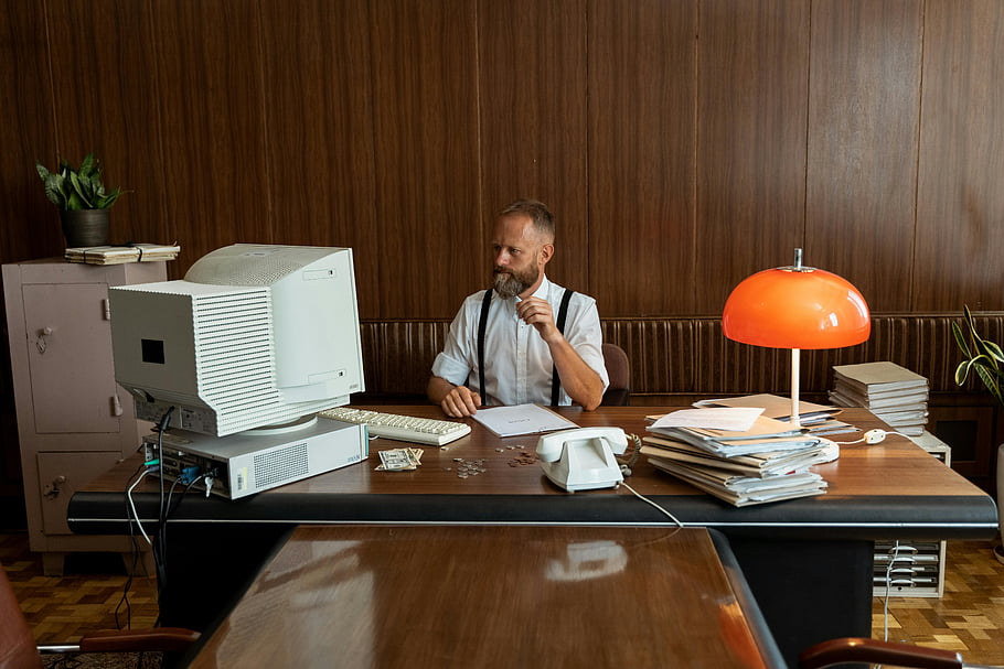 businessman, computer monitor, vintage office, retro computer, 80s business, desk lamp, office decor, man working, office setting, 1980s style, workspace