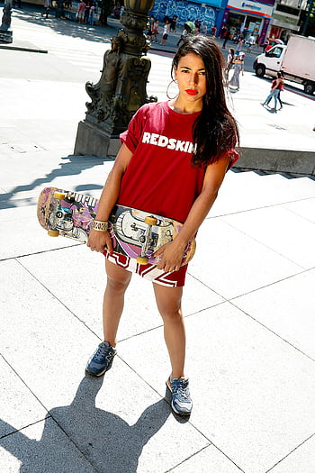 woman, red shirt, skateboard, urban setting, street fashion, confident, young woman, holding skateboard, casual style, city life, streetwear