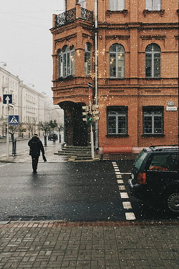 pedestrian, snow-covered street, historic brick building, winter, street corner, walking, snowy day, urban scene, cityscape, traffic light, car