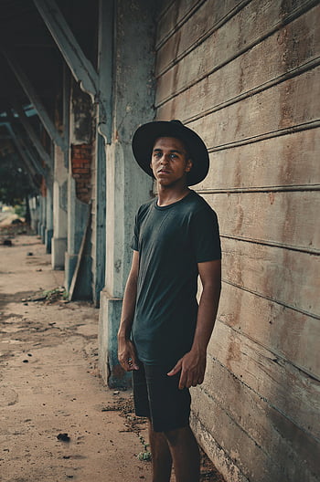 om, negru tricou, pantaloni scurti, fedora, care prezintă, structura din lemn, în aer liber, tânăr, pălărie neagră, Stil casual, urban
