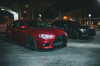 Červený Mitsubishi Lancer Evo, černé Subaru Impreza, luxusní auta, zaparkované vedle sebe, noční město světla, městské parkování, vysoce výkonná vozidla, Automobiloví nadšenci, automobilové fotografie, pouliční scény, noční scénu