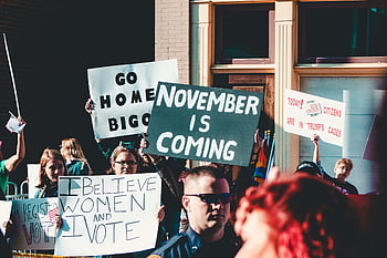 street protest, diverse group, impactful signs, people holding banner, building, dynamic protest, protest signs, public demonstration, social activism, political rally, outdoor protest