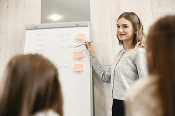 female teacher, whiteboard, flipchart, classroom, explaining notes, smiling, education, teaching, students, lesson, presentation
