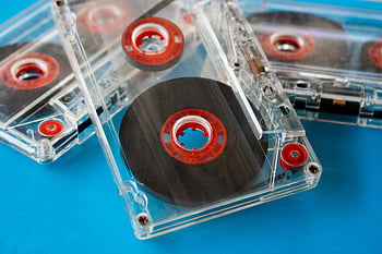 cassetes de áudio transparentes, bobinas vermelhas, fundo azul, Cassetes vintage, fechar-se, foco seletivo, cassetes compactas, fita visível, áudio retrô, armazenamento de música, mídia de áudio