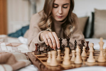 žena hrající šachy, mladá žena šachy, strategický šachový tah, Vnitřní šachová hra, soustředěný šachista, desková hra šachy, Šachová strategie, šachová figurka, vnitřní šachová scéna, zaměření na šachovou hru, příležitostná šachová hra