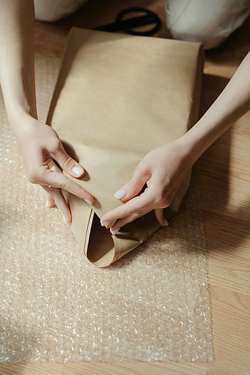 hands wrapping package, protective bubble, kraft paper, close-up hands, package wrapping, bubble wrap, kraft wrapping paper, gift wrapping, hands close-up, protective packaging, bubble wrap sheet