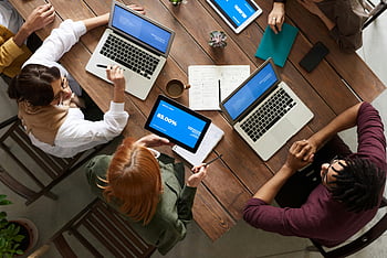 felülnézet, ember csoport, A MacBook használata, megbeszélése, változatos csapat, üzleti stratégiák, laptopok, tabletta, faasztal, együttműködési találkozó, irodai környezet