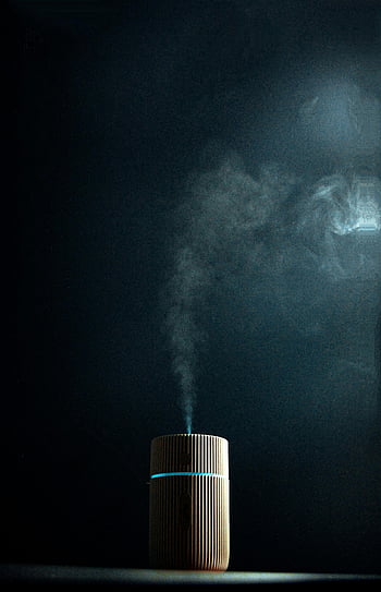 fragrance diffuser, dark background, wooden diffuser, emitting steam, soothing ambiance, essential oil diffuser, aromatherapy device, steam emission, dark ambiance, wooden texture, relaxation tool