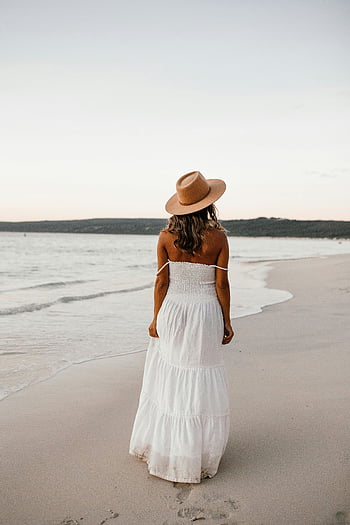 woman in white dress, beach sunset, empty beach, woman walking beach, white dress, beach hat, sunset beach, woman in hat, beach scene, beach walk, sunset walk
